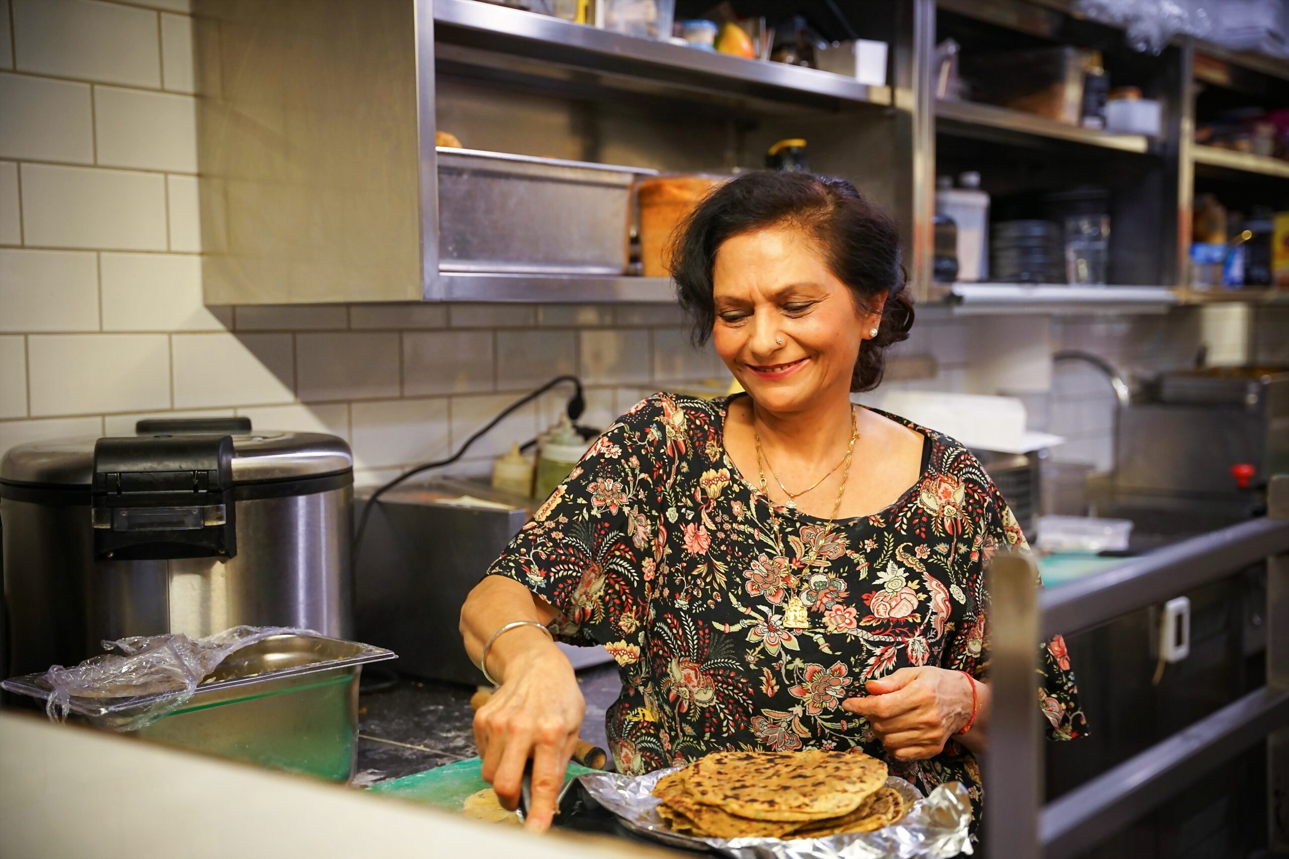 Muttern skjærer opp en fylt paratha ved kjøkkenpasset i det åpne kjøkkenet